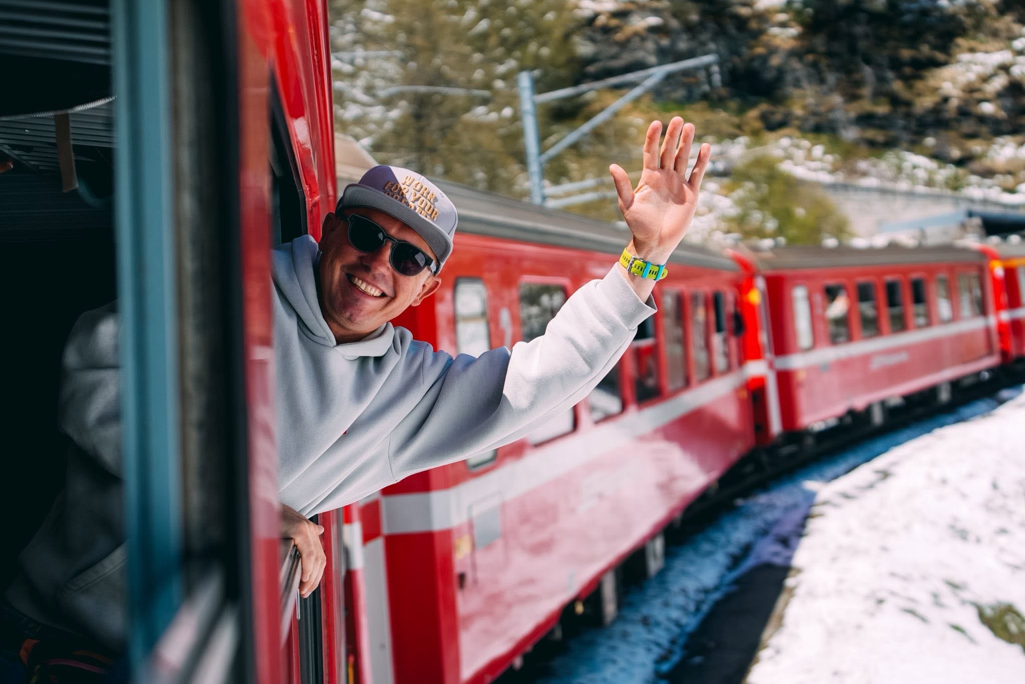 Podróżny machający z czerwonego pociągu na trasie Bernina